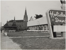 Het Holiday Inn hotel anno 1973. Op de achtergrond de St. Antoniuskerk die op dat moment wordt gesloopt. Het dak is al grotendeels ontmanteld. Foto: A. Hagen, Technische Dienst gemeente Eindhoven | Beeldcollectie RHCe